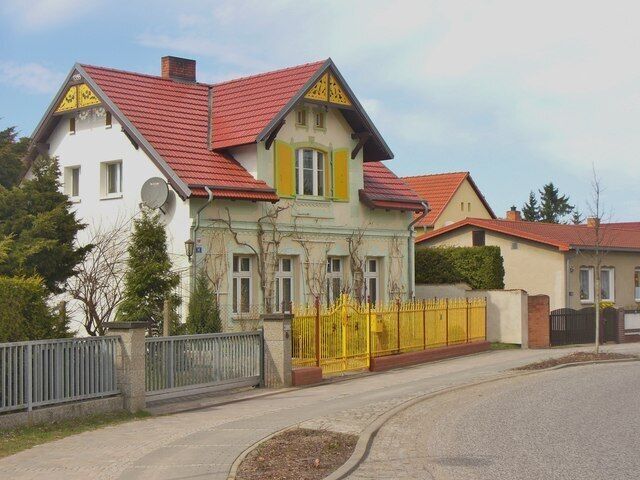 A row of houses with red roofs and a yellow fence.