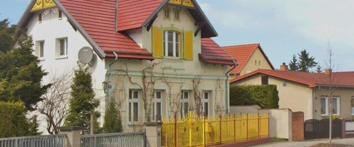A row of houses with red roofs and a yellow fence.