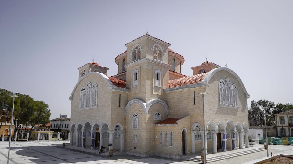 Uma igreja grande e histórica com telhado de telhas vermelhas e várias janelas em arco.