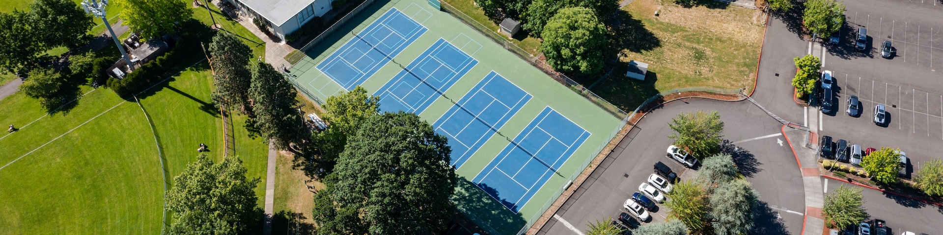 High resolution aerial drone picture of outdoor tennis courts and green fields near a high school in Cedar Mill, Portland, Oregon, captured on a clear summer day