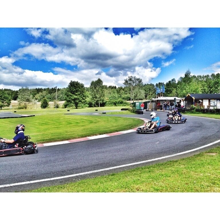 Go-karts racing on a track surrounded by grass and trees.