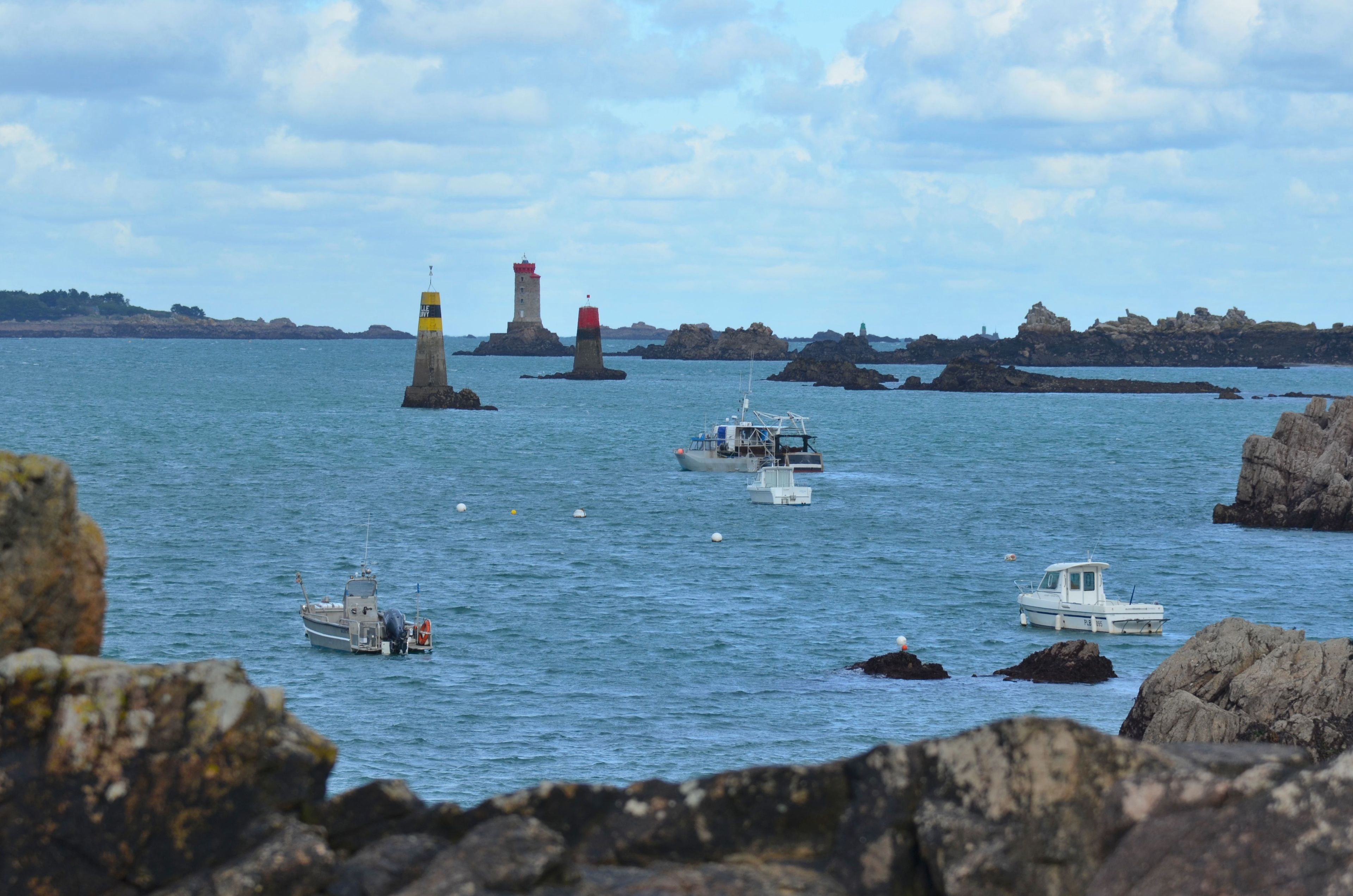 A coastal scene with lighthouses, boats, and rocky outcrops.