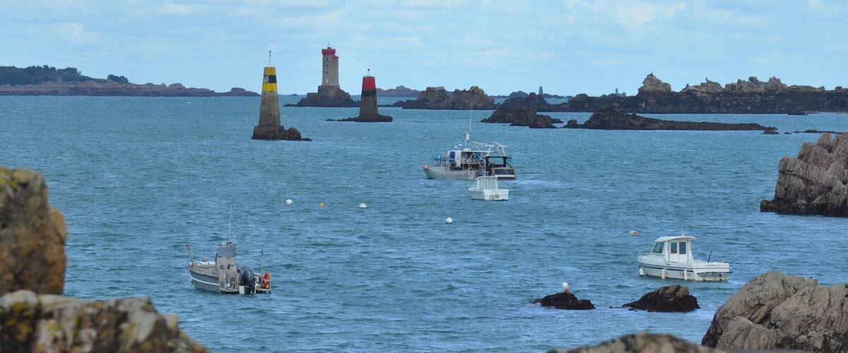 A coastal scene with lighthouses, boats, and rocky outcrops.