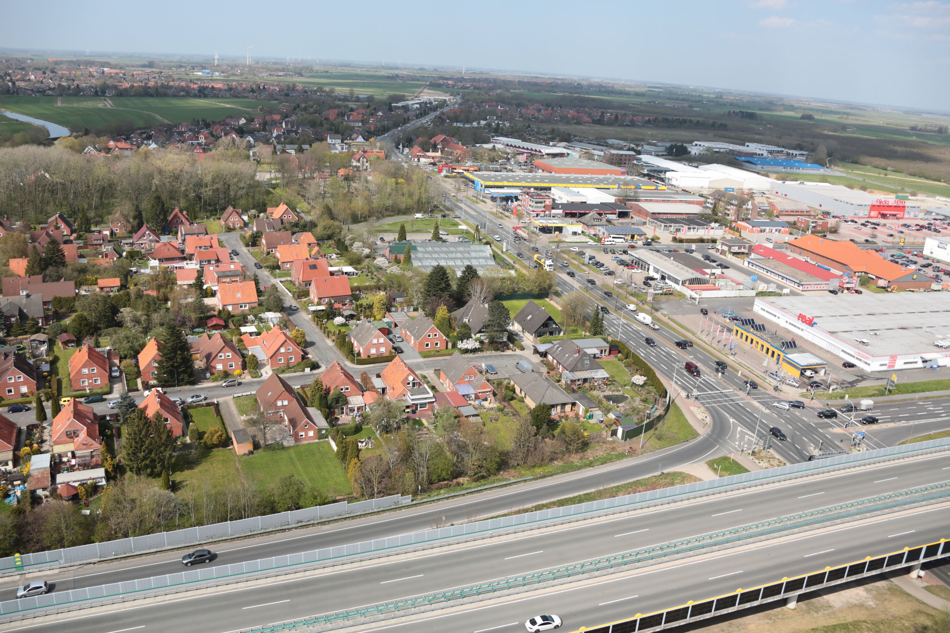 An aerial view of a town with red-roofed houses, a highway, and industrial buildings.