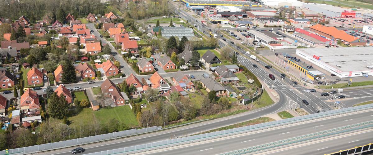 An aerial view of a town with red-roofed houses, a highway, and industrial buildings.