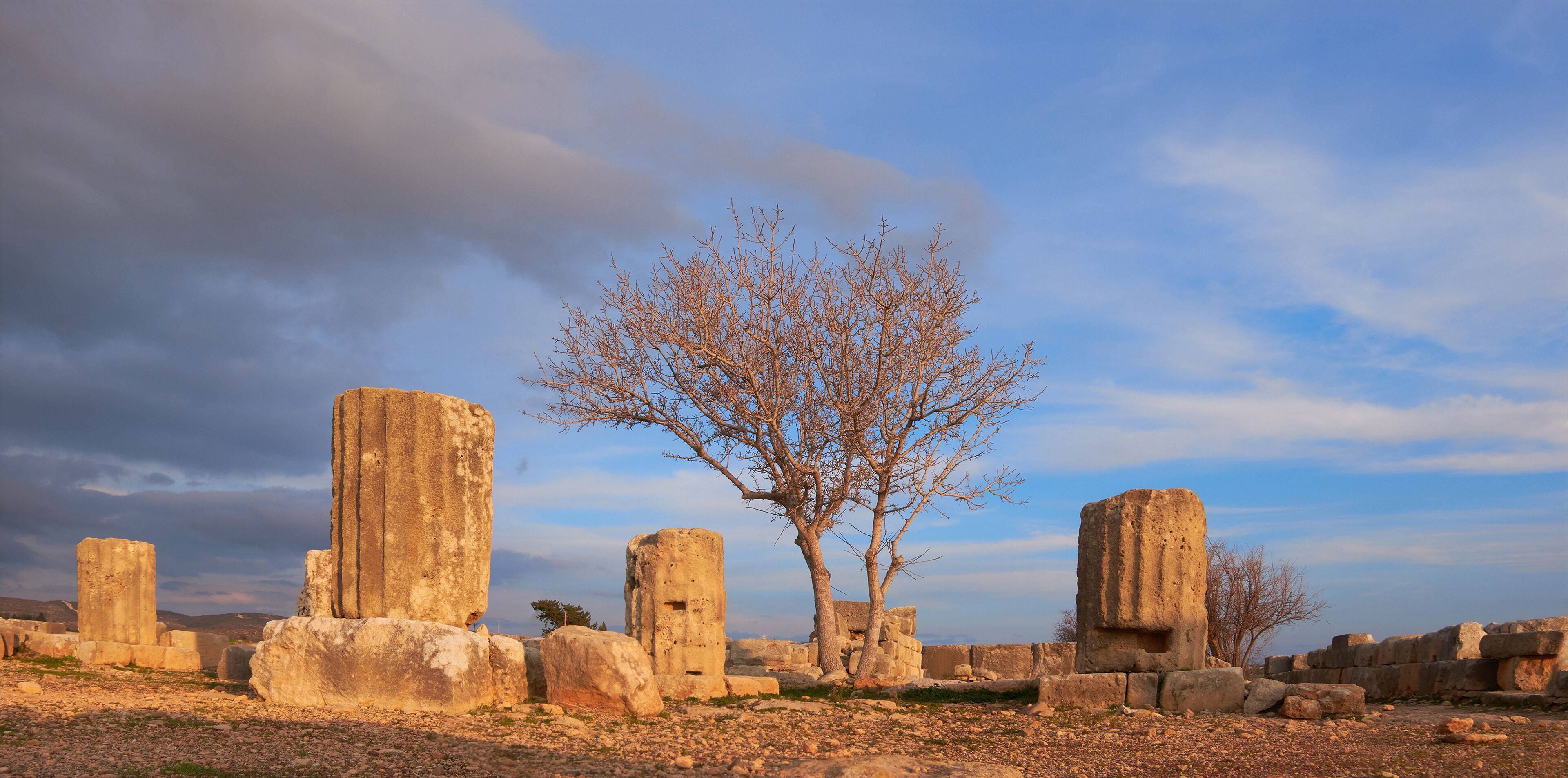 ruins of the famous Temple of Aphrodite under dramatic sky Old Paphos Cyprus, hills in the background