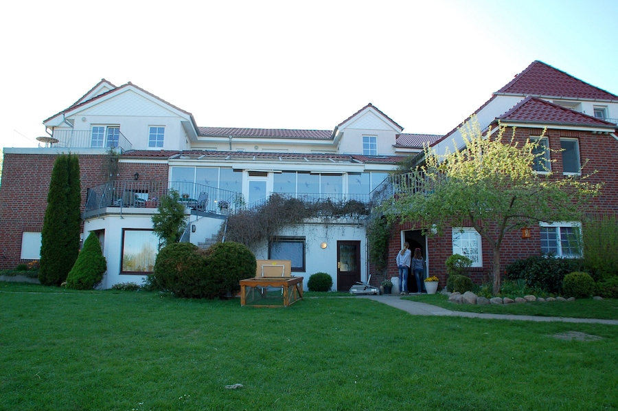 Ein zweistöckiges Haus mit Backsteinfassade, einer Veranda und einem gepflegten Rasen.