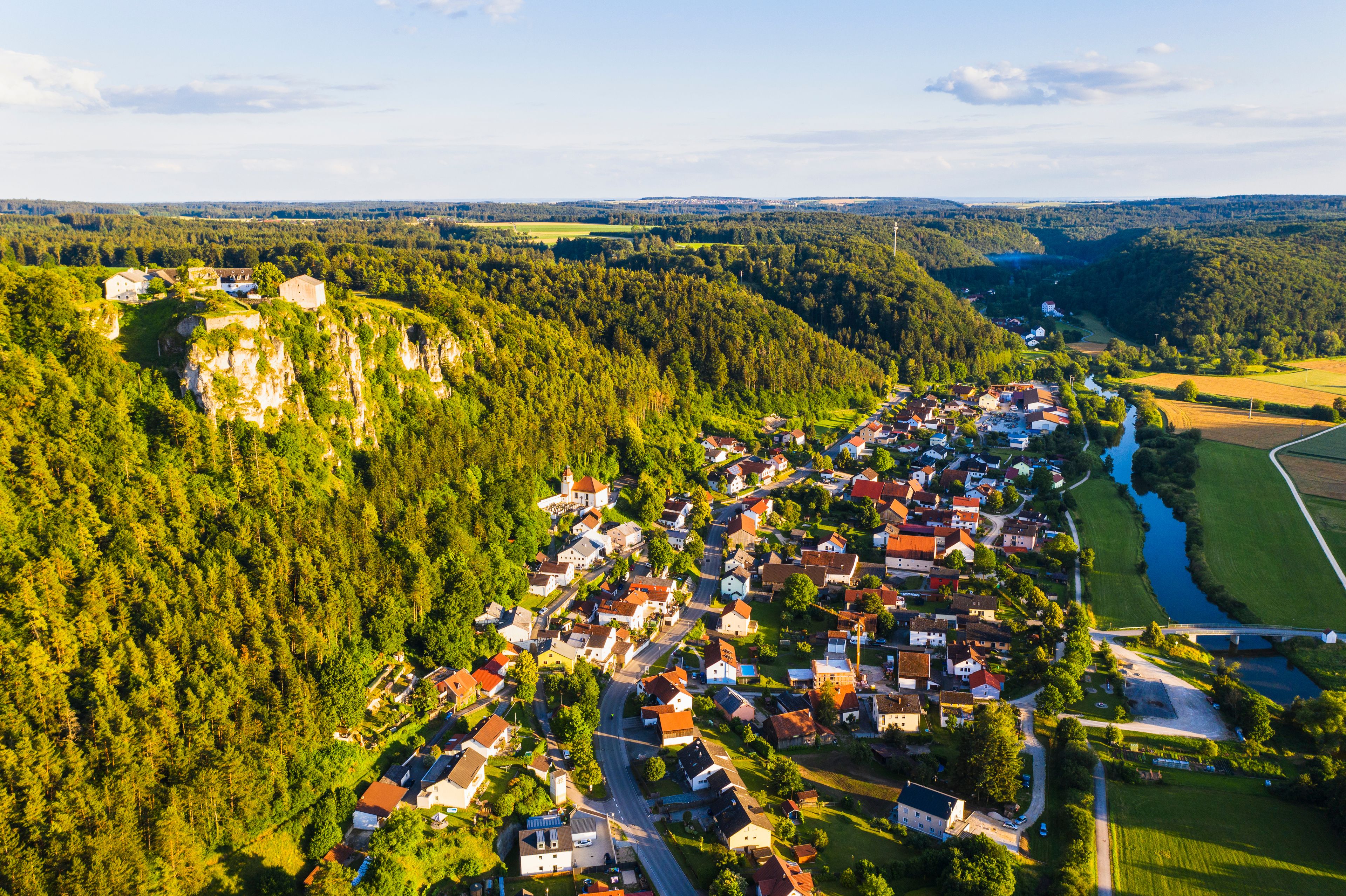 A village nestled in a valley with a river running through it.