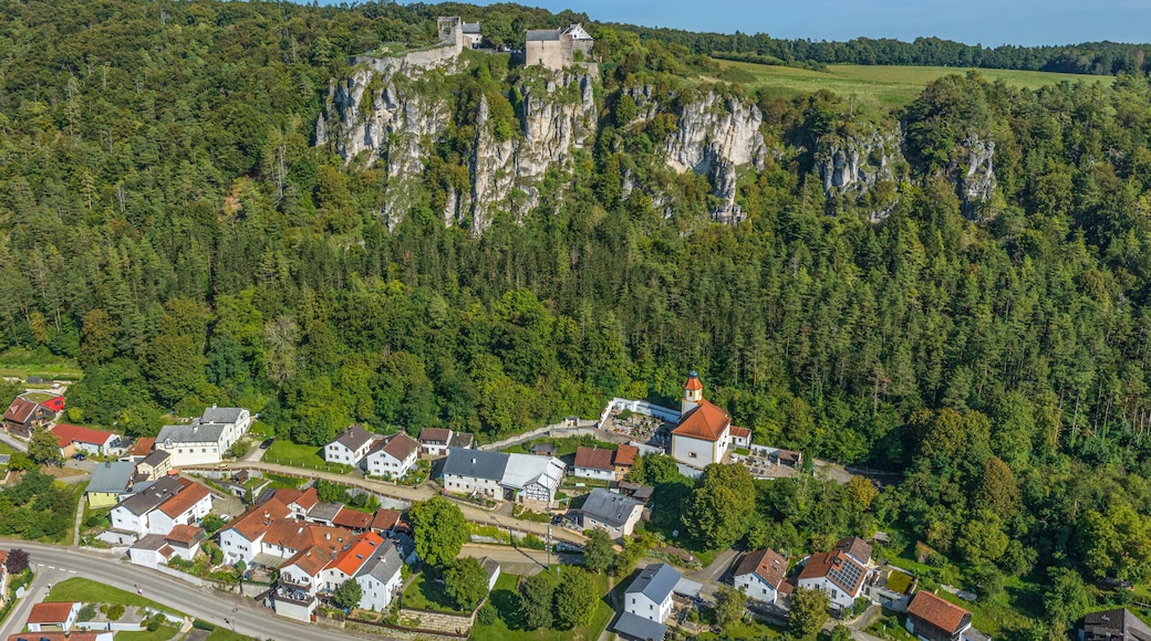 A village nestled in a valley with a prominent castle on a rocky hill in the background.