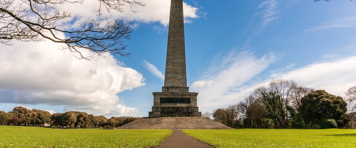 Scene framed by tree branches at the Wellington Monument and Testimonial (finished in 1861), the largest obelisk in Europe located in Phoenix Park, Dublin, Ireland, on a spring morning.