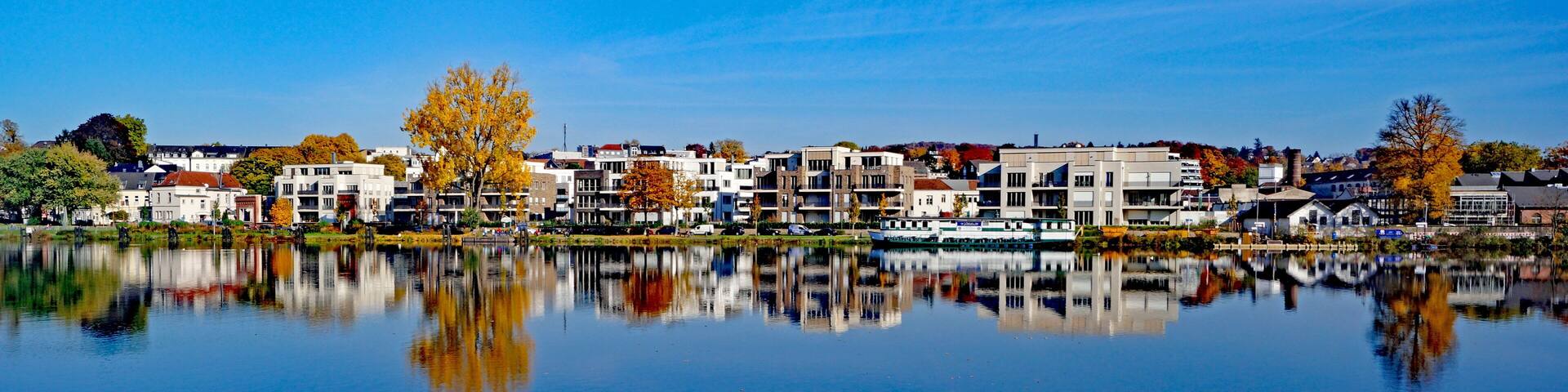 A calm lake reflecting buildings and trees.