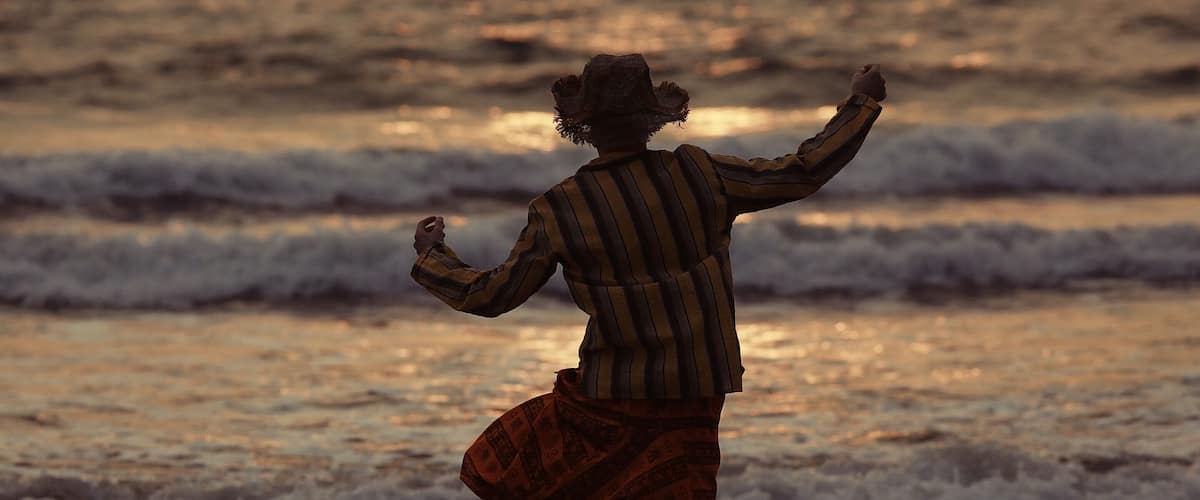 A person walking on a beach with waves in the background.