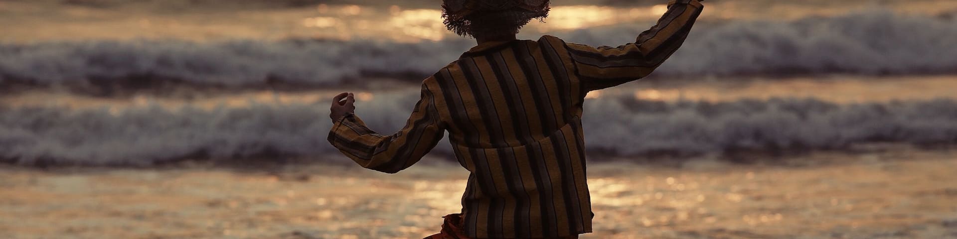 A person walking on a beach with waves in the background.