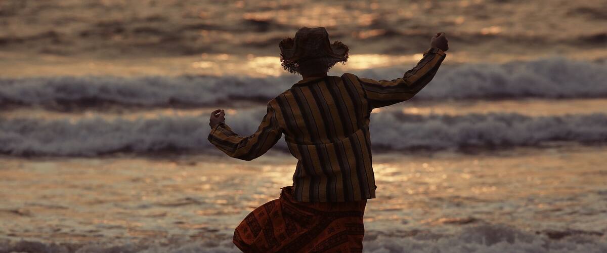 A person walking on a beach with waves in the background.