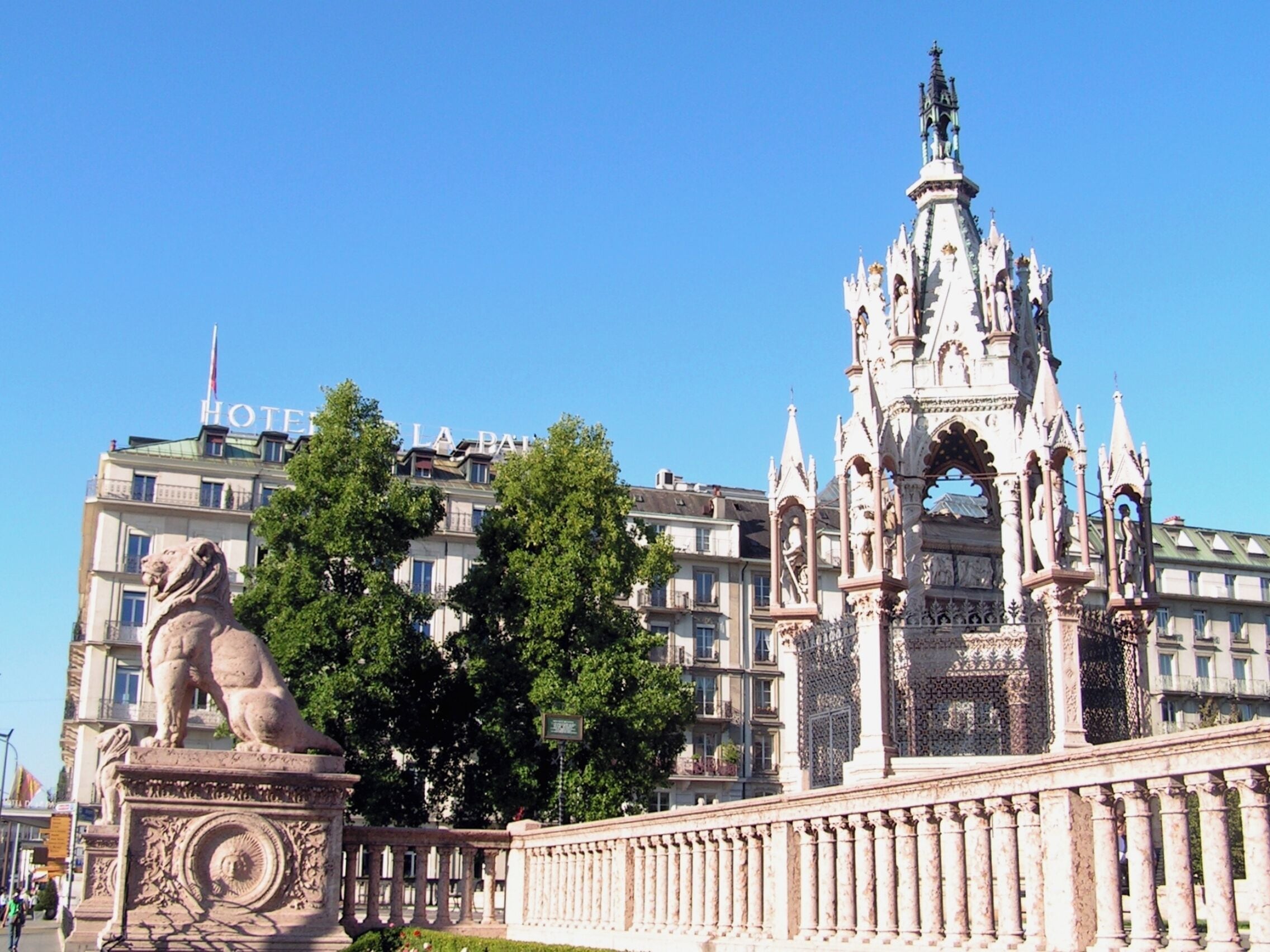 Un bâtiment historique à l’architecture riche et ornée, une statue de lion et un ciel d’un bleu éclatant.