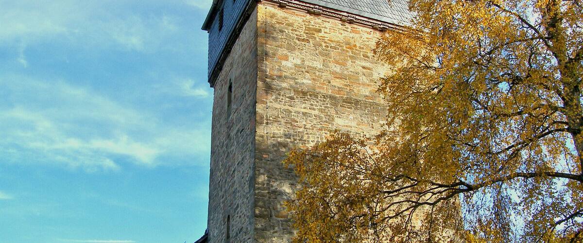 A historic stone church with a tall steeple and a weather vane.