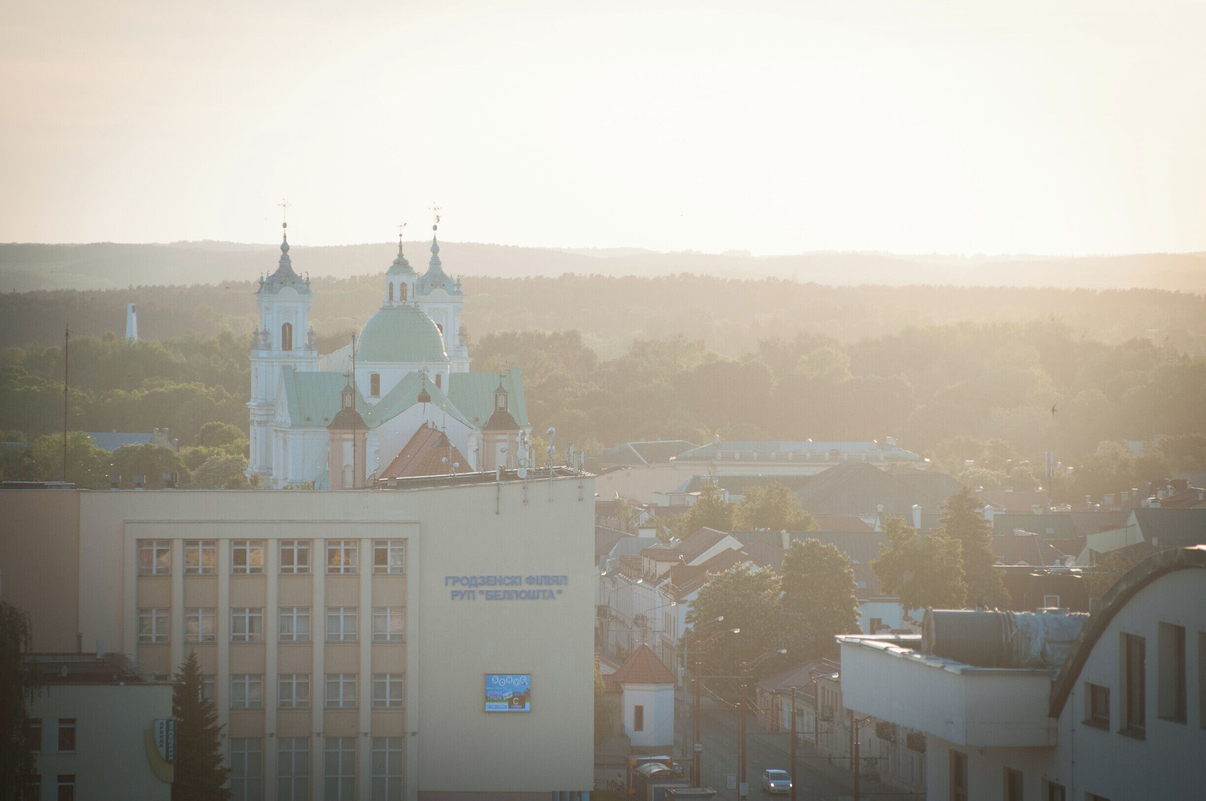 A church with two domes and a bell tower, surrounded by buildings and trees.