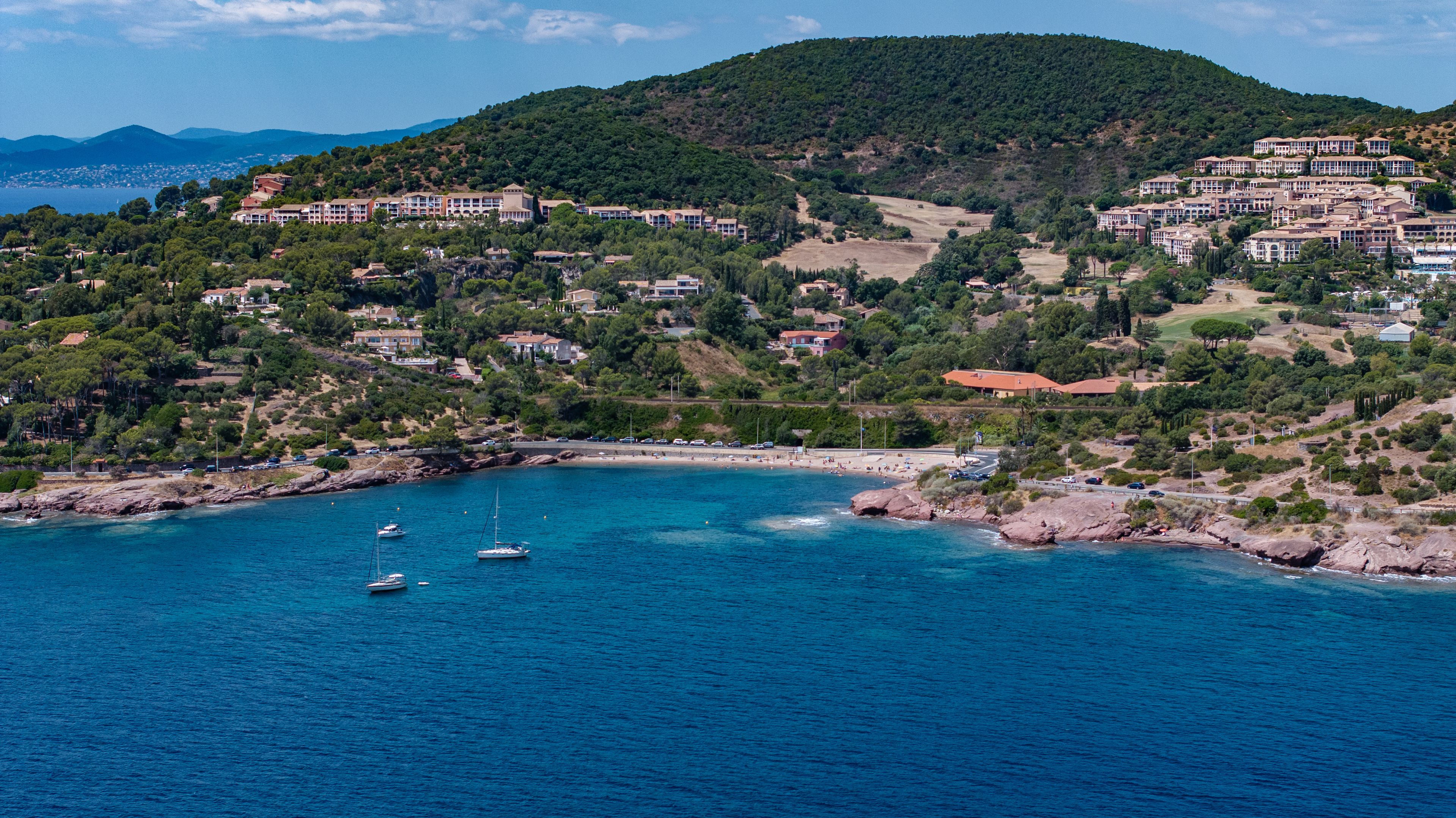 aerial landscape view of area around"Plage du Pourrousset" Beach at Agay Bay, French Riviera (Côte d'Azur) with Village Cap Estérel in Saint-Raphaël and wooded hilly landscape in background 