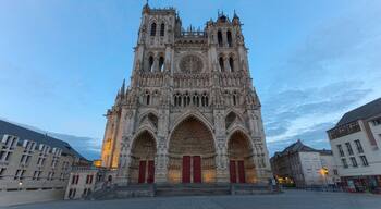 Una catedral gótica con dos torres, una fachada intrincada y puertas rojas.