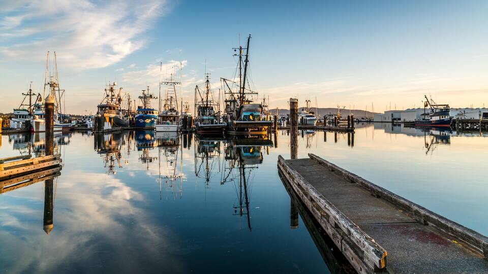 Bellingham, Washington / USA. 06. 17. 2018. Pond mirroning in the waters of the Pacific ocean with boats in the background.