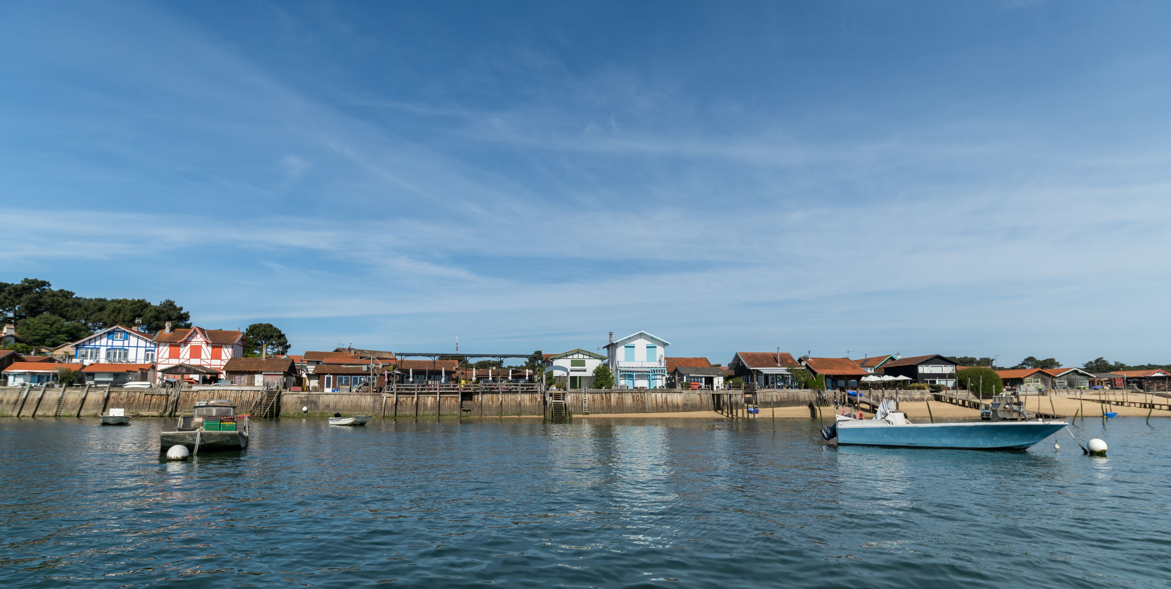 A coastal town with houses, boats, and a wooden pier.