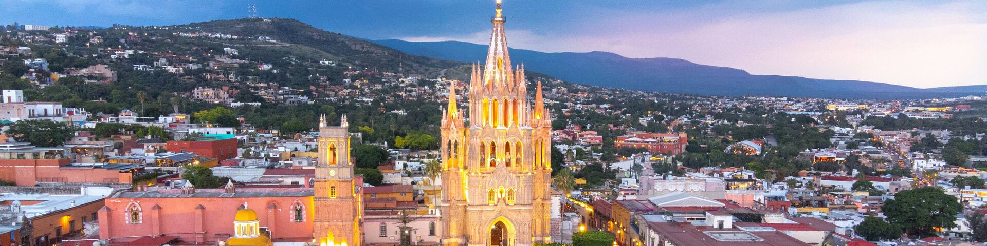 the church Parroquia Archangel Jardin Town Square Night Tree Decoraciones San Miguel de Allende, México. Parroaquia. Night and morning light in a drone view.
