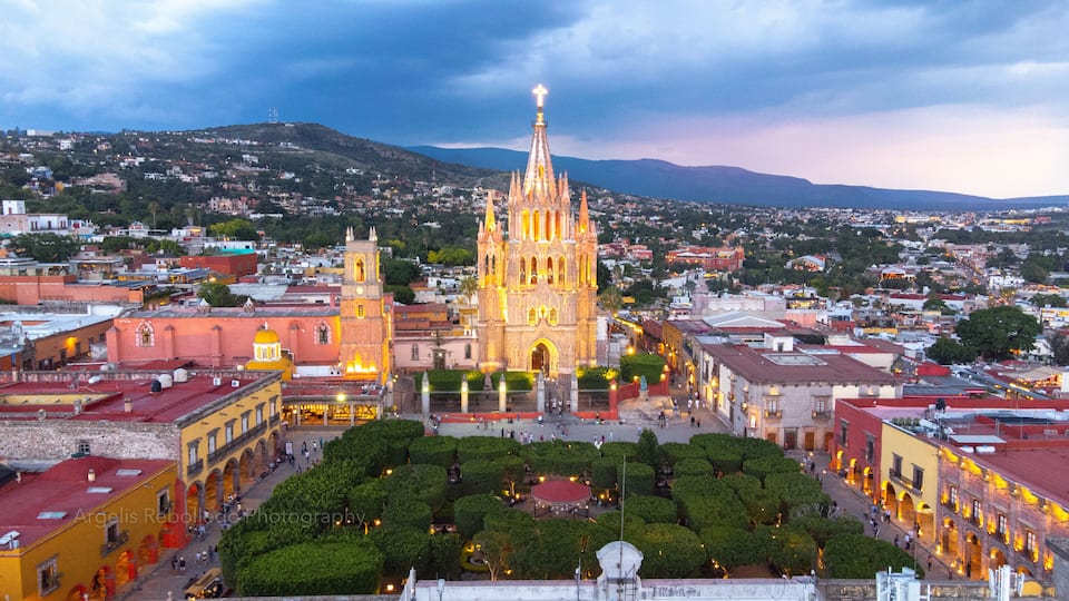 the church Parroquia Archangel Jardin Town Square Night Tree Decoraciones San Miguel de Allende, México. Parroaquia. Night and morning light in a drone view.