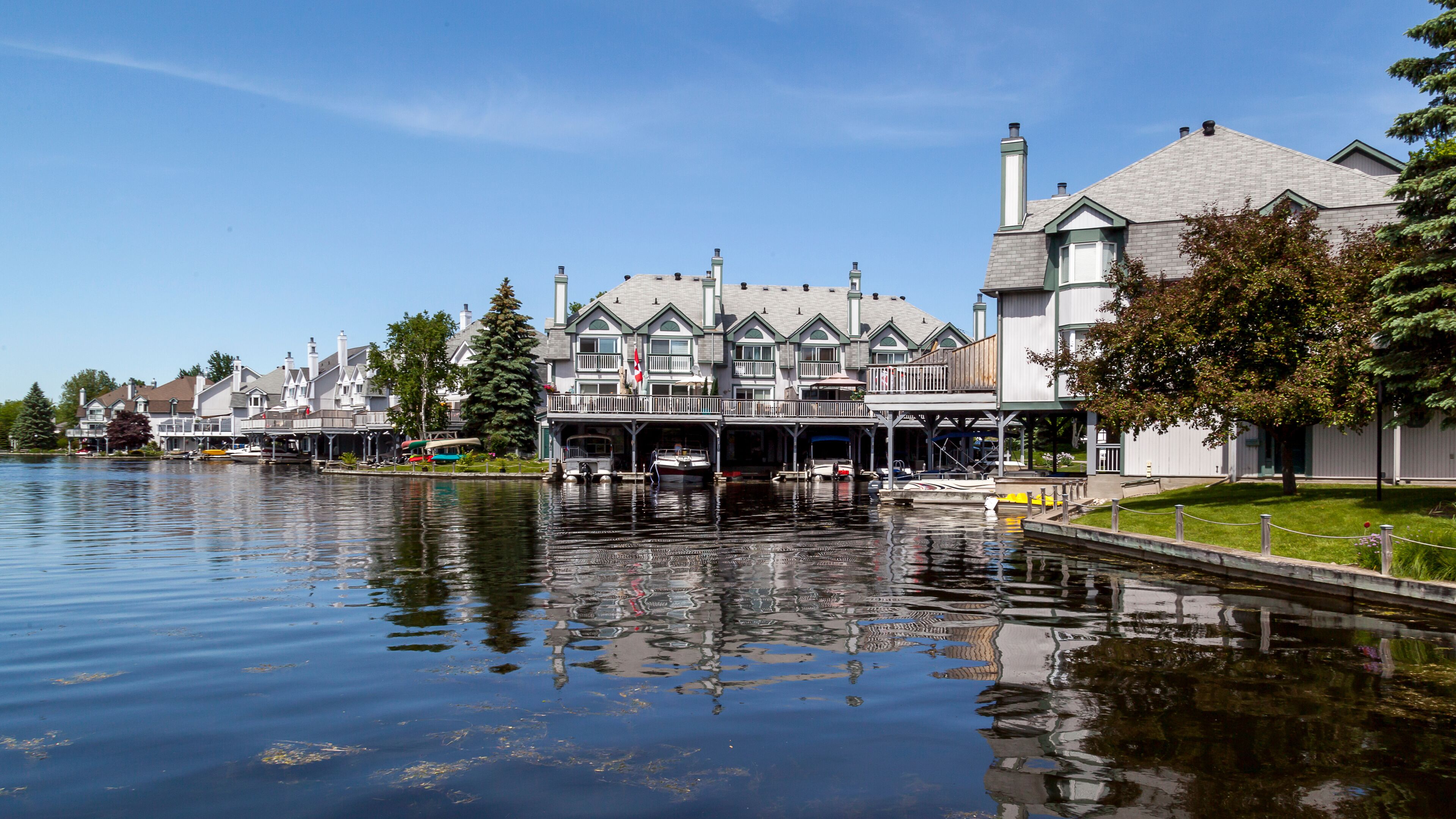 A waterfront with buildings, boats, and a calm river.