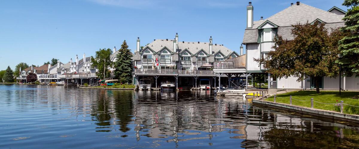A waterfront with buildings, boats, and a calm river.