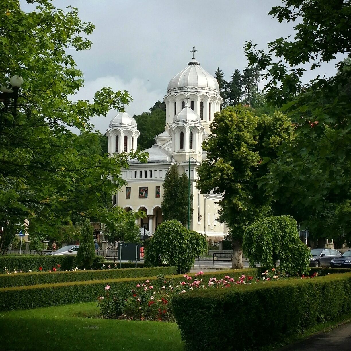 A large white church with domes, surrounded by well-maintained gardens and trees.