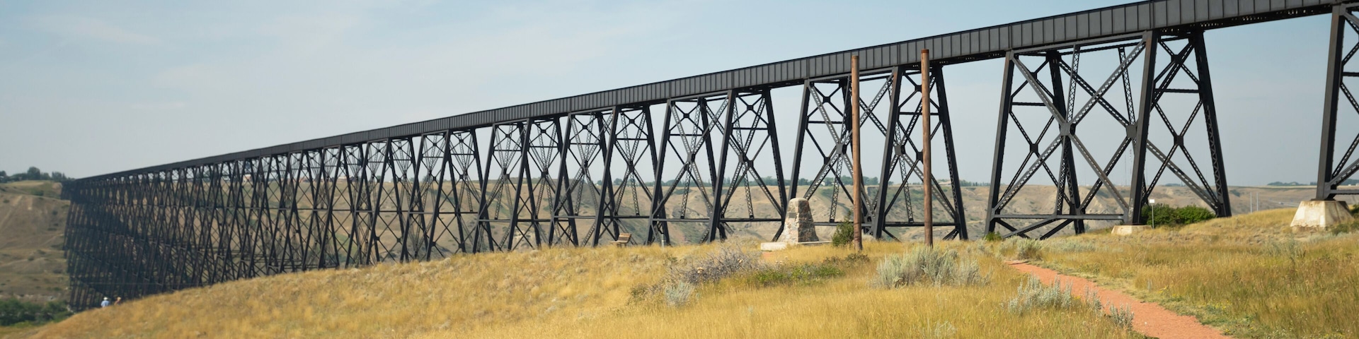 A long steel bridge spanning a dry, grassy landscape with a clear sky.
