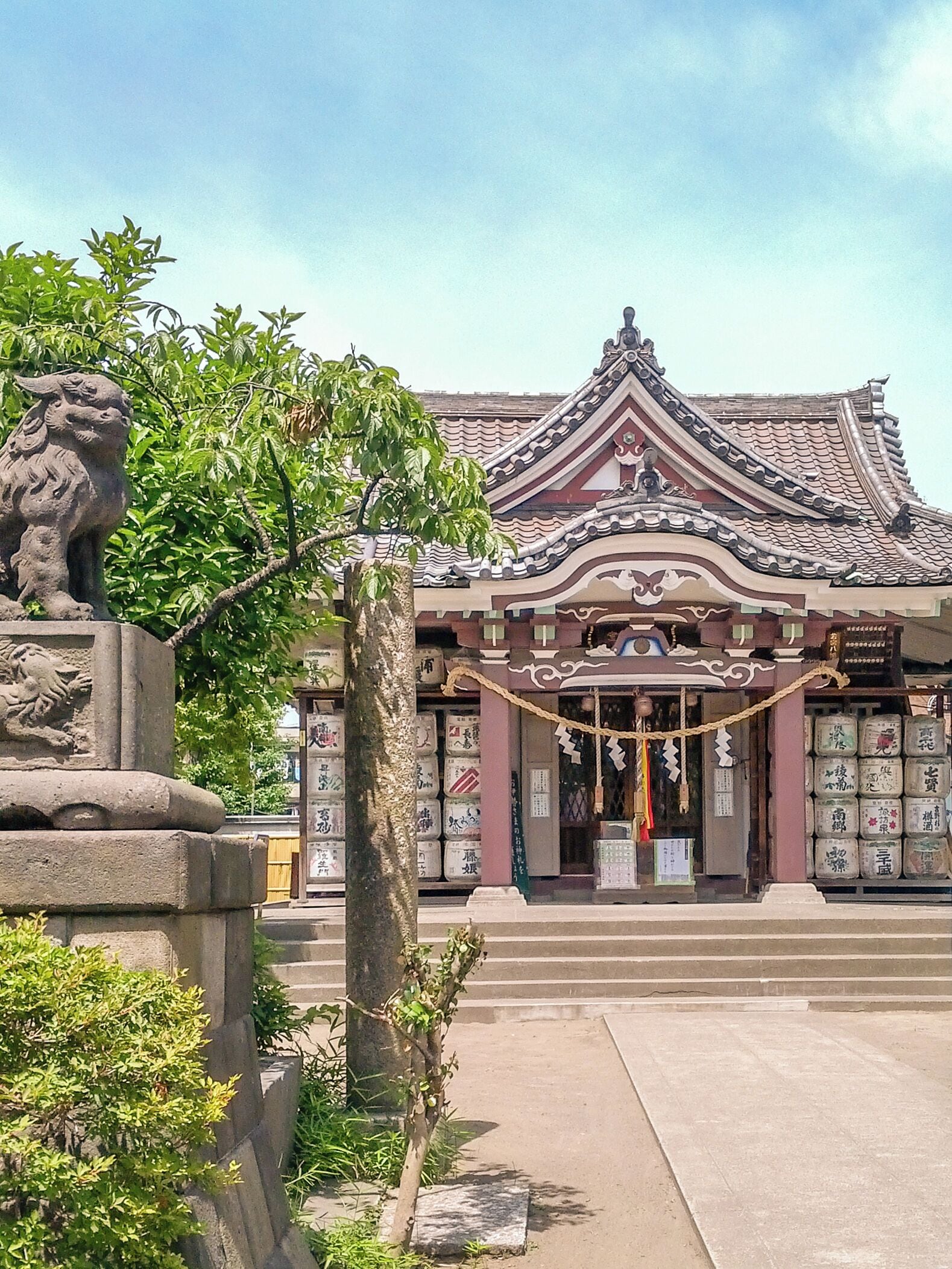 A traditional building with a tiled roof and a stone lion statue in front.