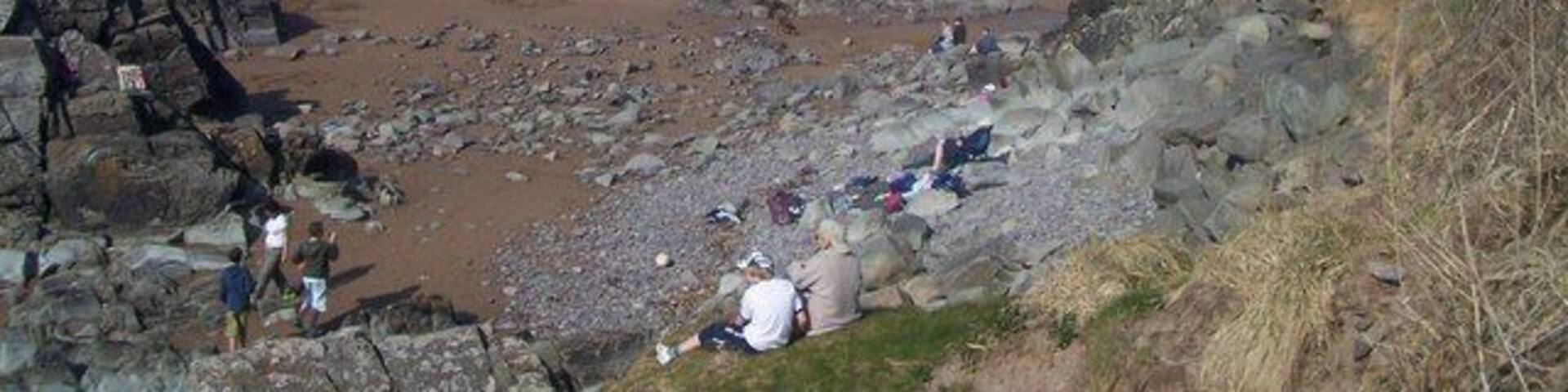 A rocky beach with people and tents.