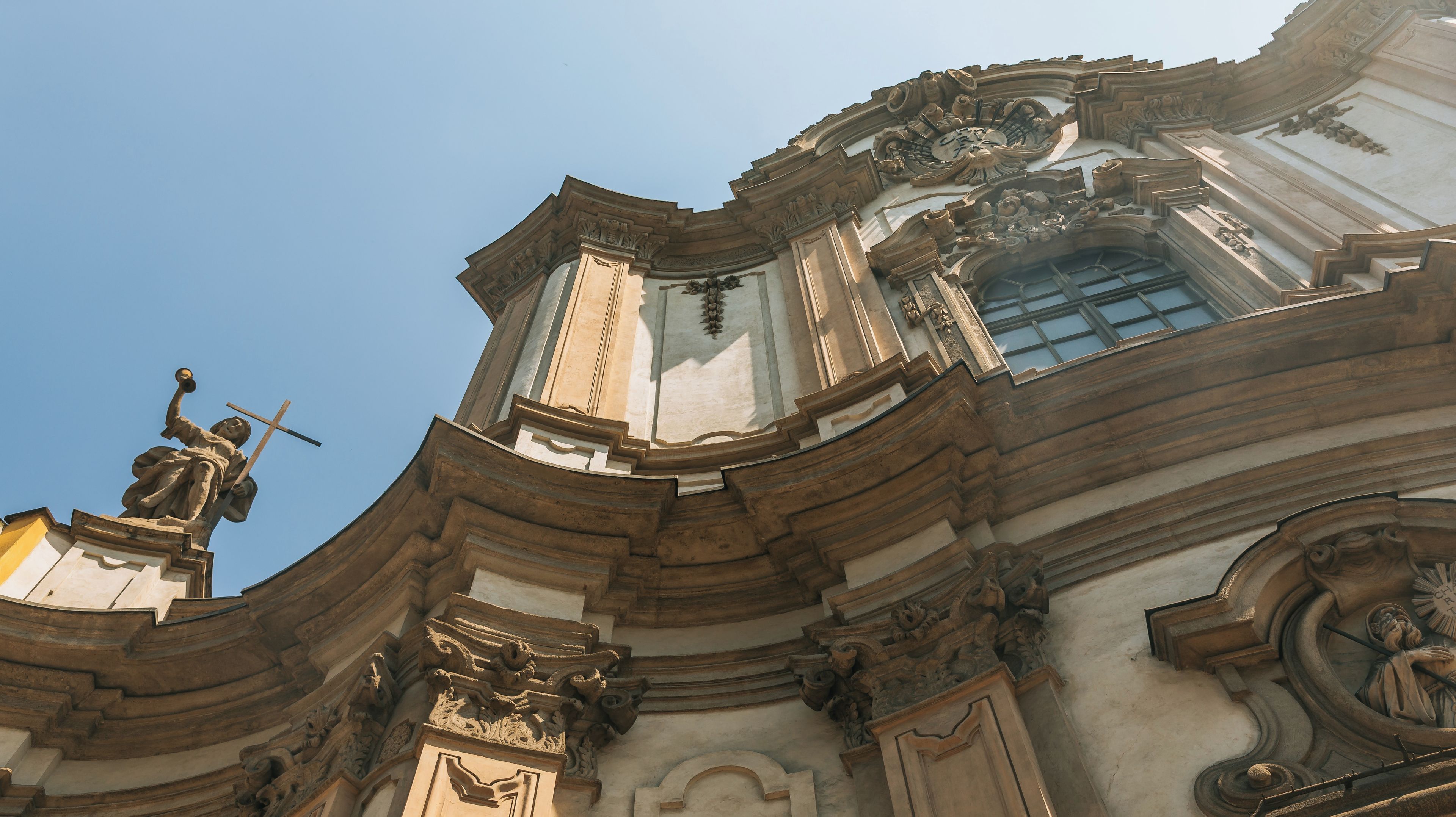 A classical building with ornate carvings and a statue of a figure holding a cross.