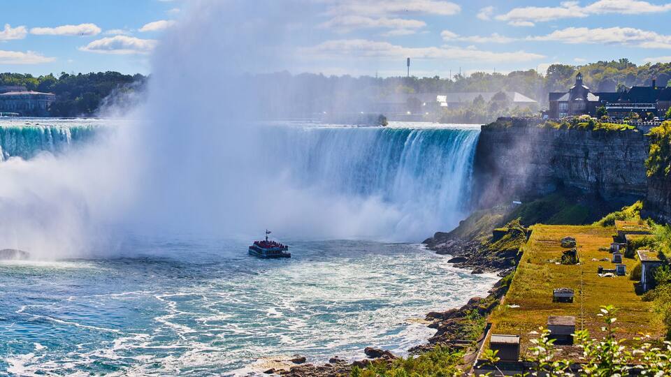 Eye level view of Niagara Falls Horseshoe Falls from Canada with mist surrounded tourist ship