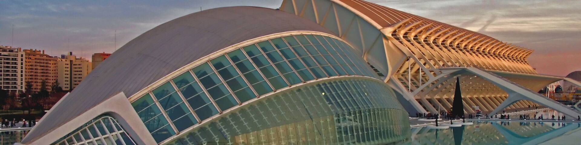 A modern architectural building with a unique curved design, reflecting in a pool.