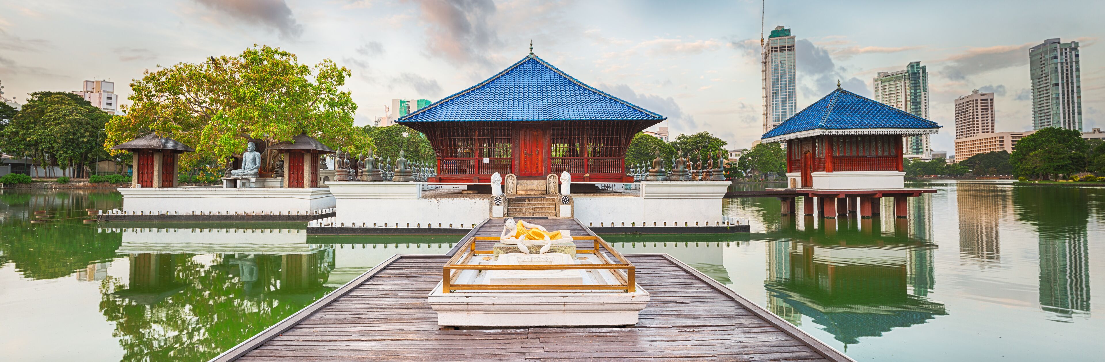A serene lakeside with traditional pavilions and a wooden boat docked at the pier.