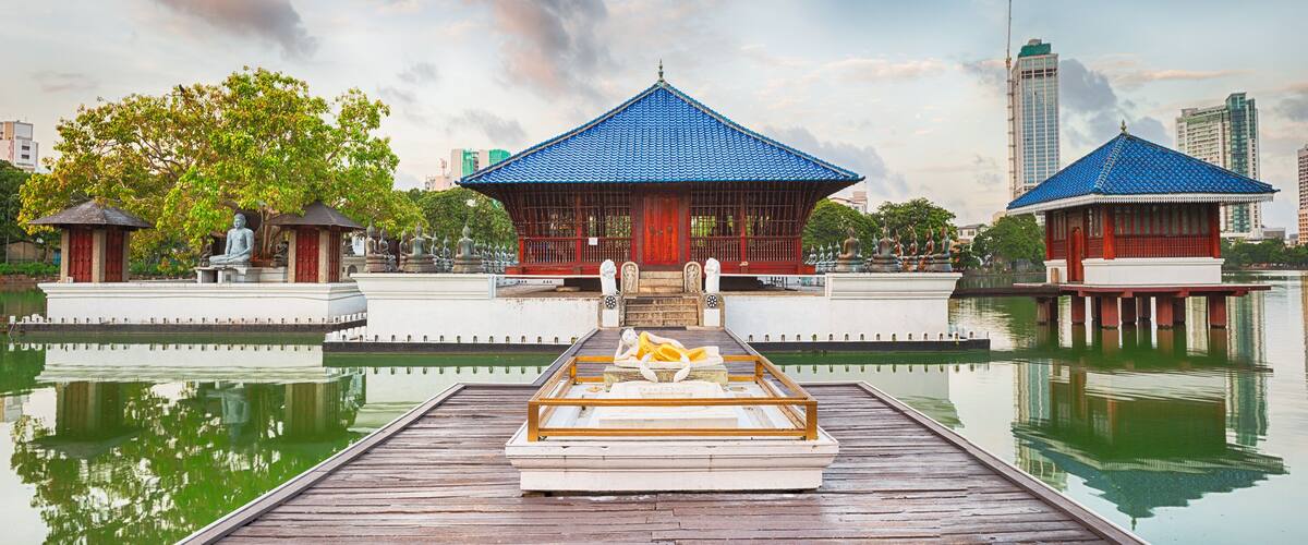 A serene lakeside with traditional pavilions and a wooden boat docked at the pier.