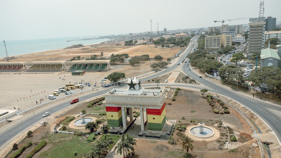 Aerial view of the iconic Black Star Gate arching proudly against the skyline with roads bustling with cars, Osu Klottey, Greater Accra Region, Ghana.