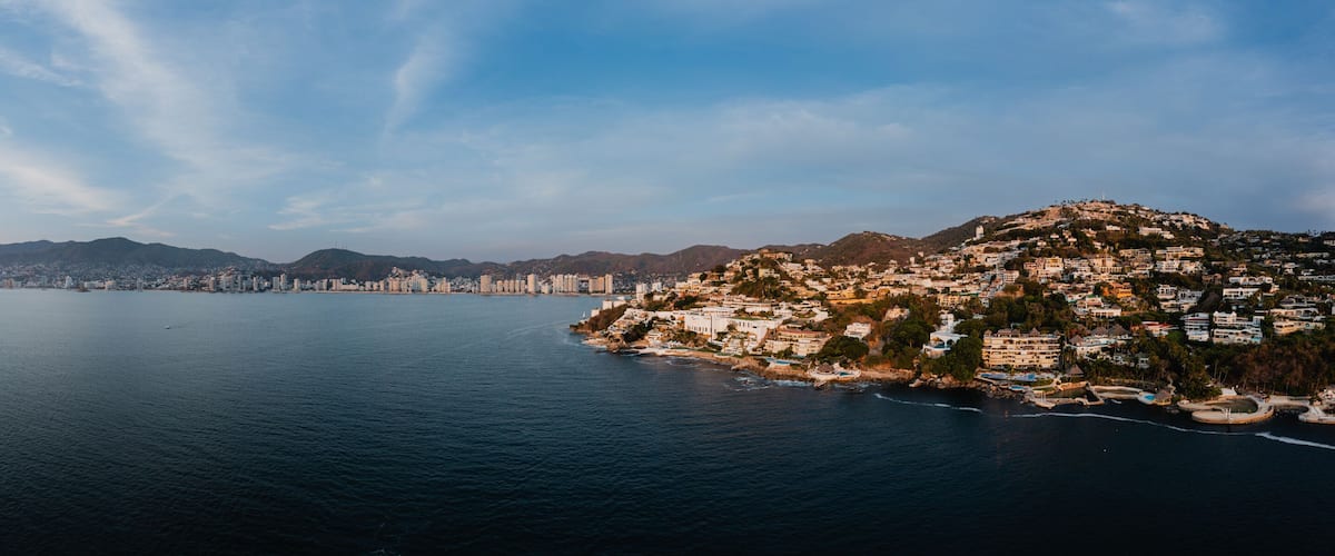 180-degree panoramic aerial photo from high altitude with a drone of Acapulco Bay in Mexico at sunset.