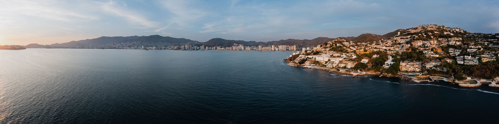 180-degree panoramic aerial photo from high altitude with a drone of Acapulco Bay in Mexico at sunset.