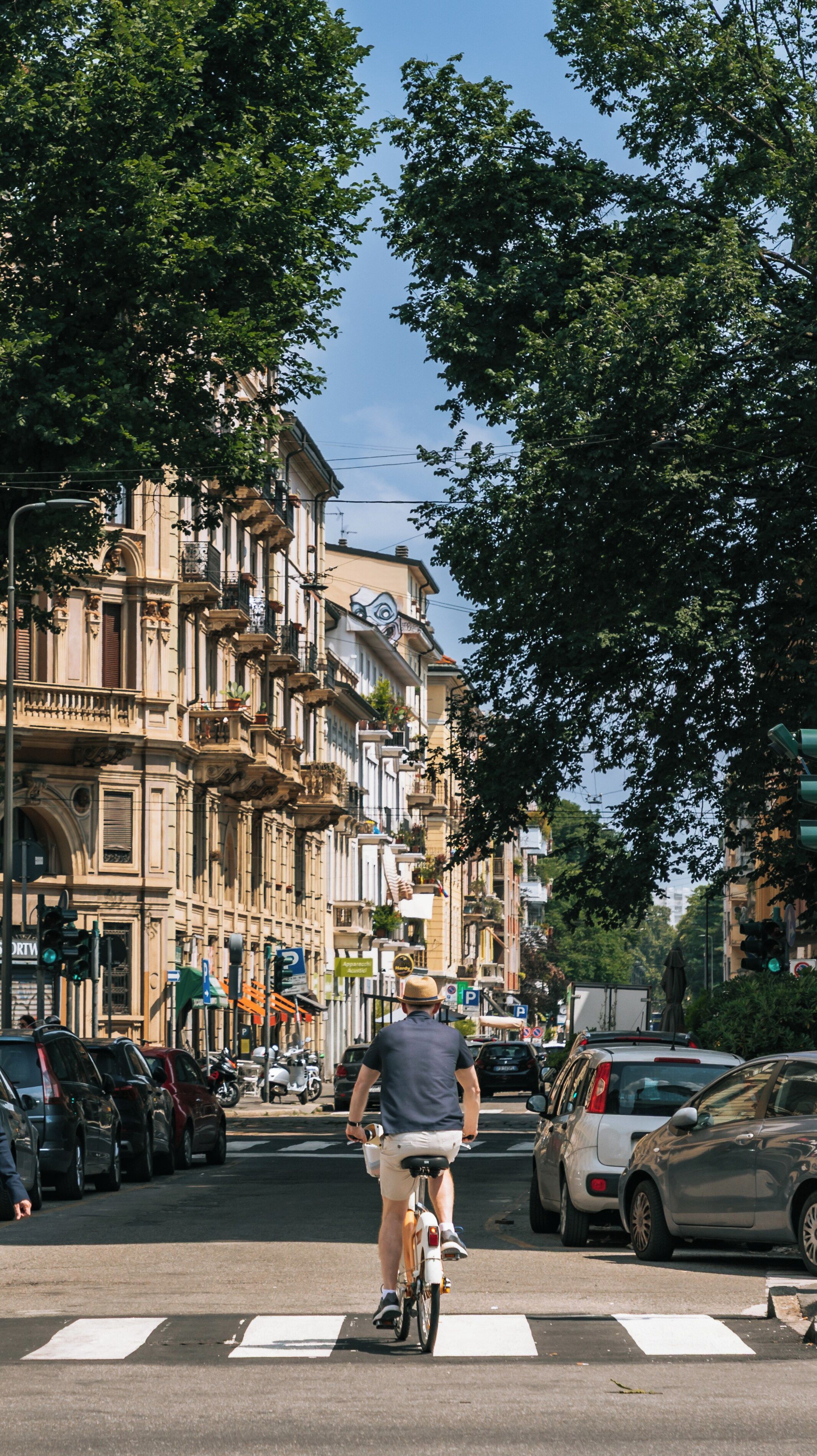 A man riding a bicycle on a city street with historic buildings and parked cars.