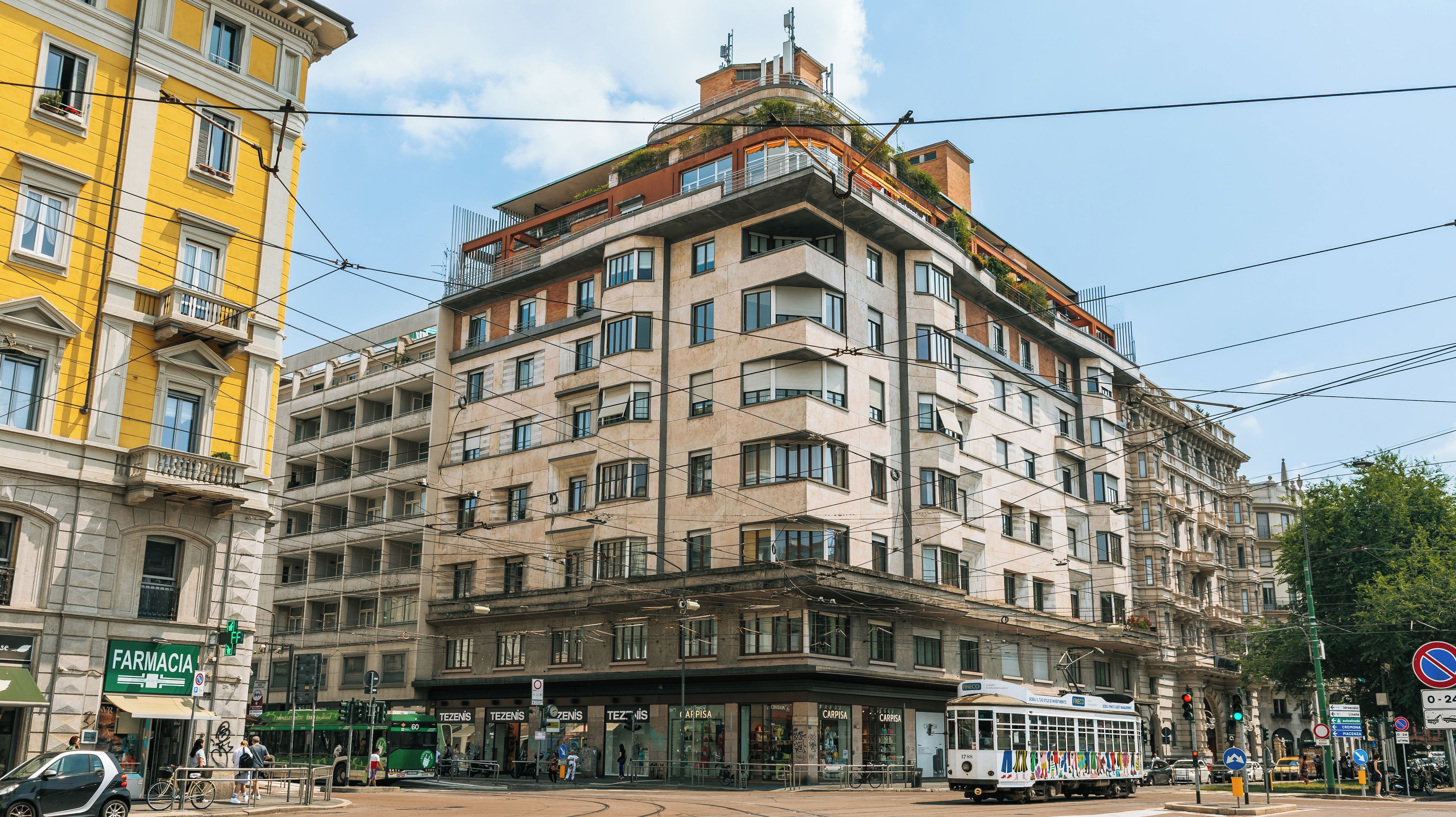 A multi-story building with a tram, street signs, and a pharmacy.