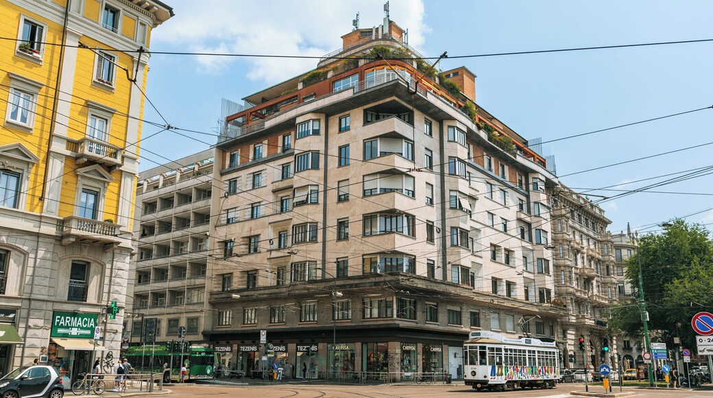 A multi-story building with a tram, street signs, and a pharmacy.