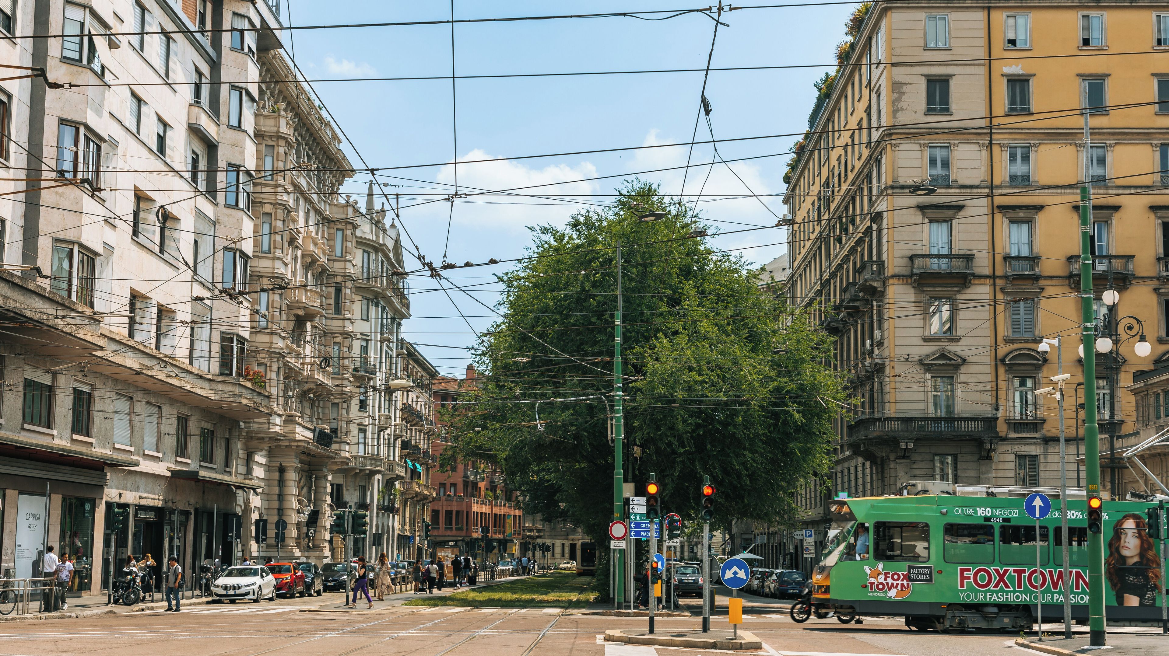 A city street with tram, buildings, and pedestrians.