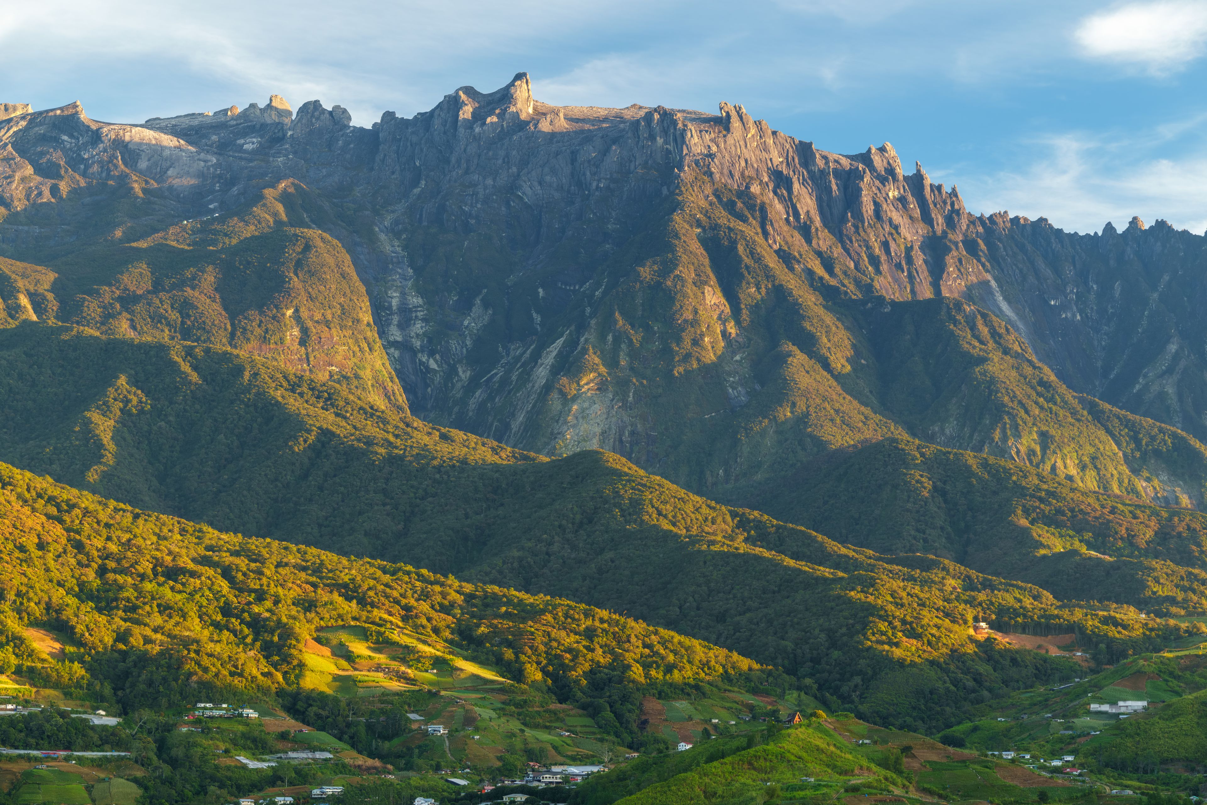 Paisatge de muntanya amb un pic rocós destacat i valls verdes i exuberants.
