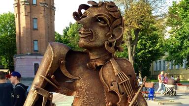 Una statua di un violinista realizzata in metallo arrugginito, situata in una piazza pubblica.