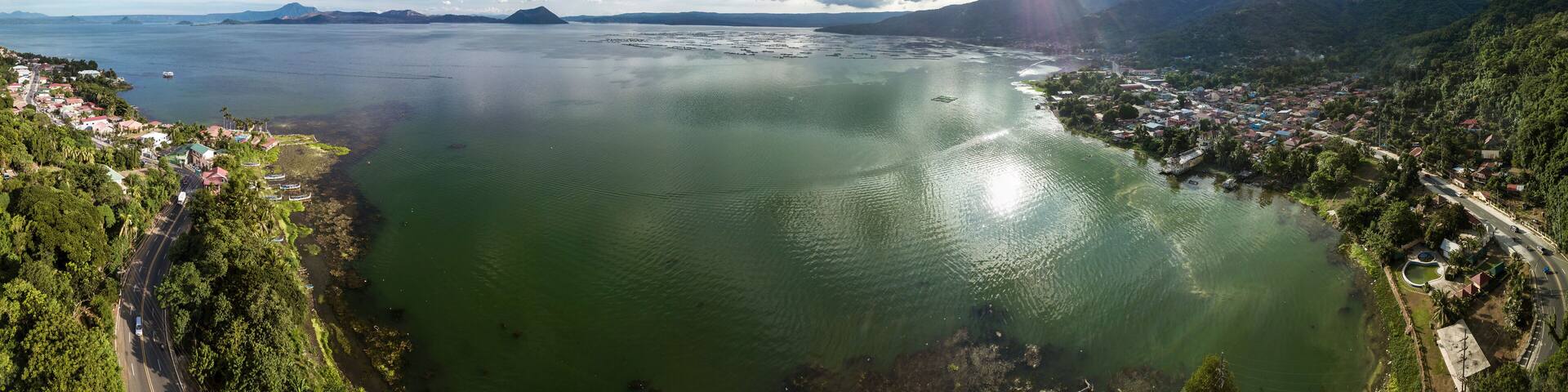 Panorama of Taal volcano and caldera, the coastline of the lake, the town of Laurel, and the Tagaytay mountain ridge.