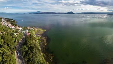 Panorama of Taal volcano and caldera, the coastline of the lake, the town of Laurel, and the Tagaytay mountain ridge.