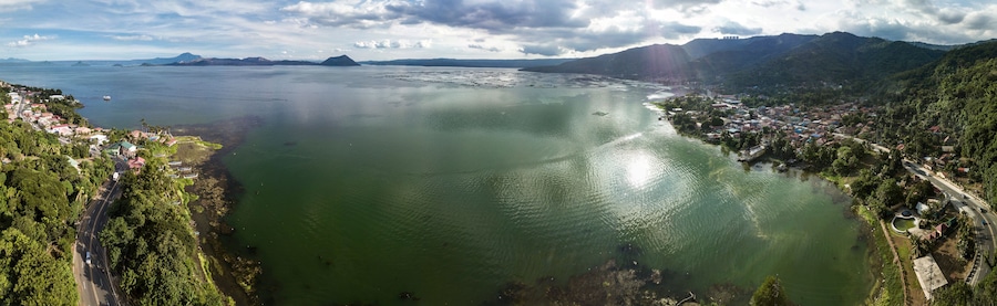 Panorama of Taal volcano and caldera, the coastline of the lake, the town of Laurel, and the Tagaytay mountain ridge.